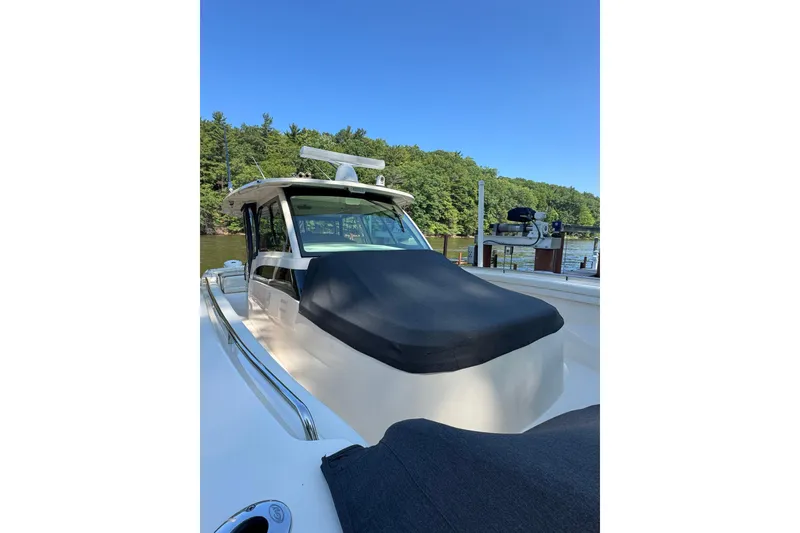 Slide: The Image of 2019 Grady-White Canyon 456 boat docked, covered, with lush greenery in the background. - 55