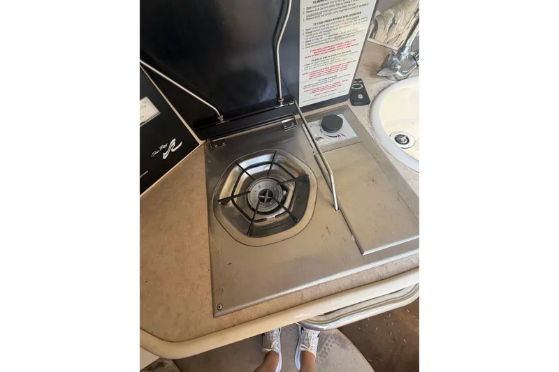 Slide: The Image of 1999 Sea Ray 240 Sundancer boat stove and sink area, featuring a compact design. - 16