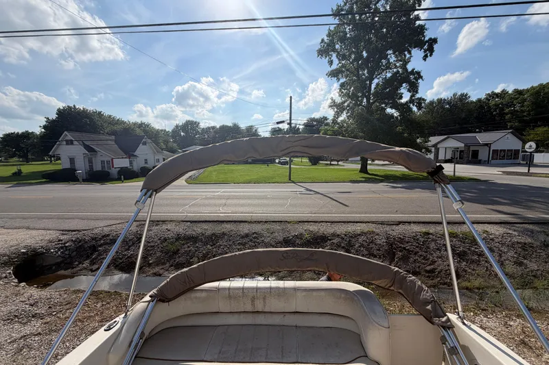Slide: The Image of 1999 Sea Ray 240 Sundancer boat with bimini top, parked near a road under a sunny sky. - 8