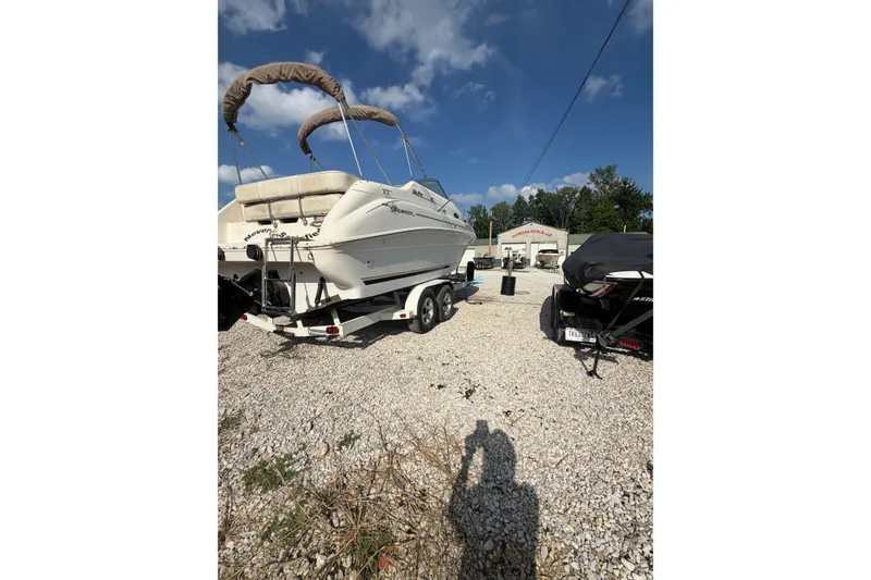 Slide: The Image of 1999 Sea Ray 240 Sundancer boat on trailer, parked outdoors under a clear blue sky. - 3
