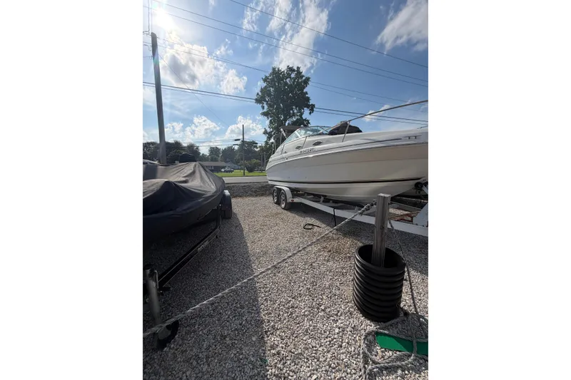 Slide: The Image of 1999 Sea Ray 240 Sundancer boat on trailer under clear blue sky. - 4
