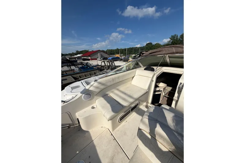 Slide: The Image of 1999 Sea Ray 240 Sundancer boat interior with seating and cabin under clear blue sky. - 10