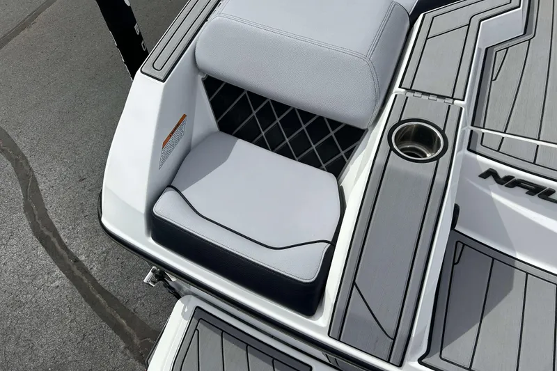 Slide: The Image of 2021 Nautique Super Air Nautique GS24 boat interior with cushioned seating and cup holder. - 5
