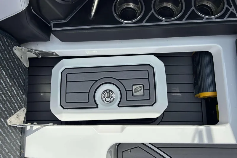 Slide: The Image of 2021 Nautique Super Air Nautique GS24 boat interior with storage compartment and cup holders. - 12