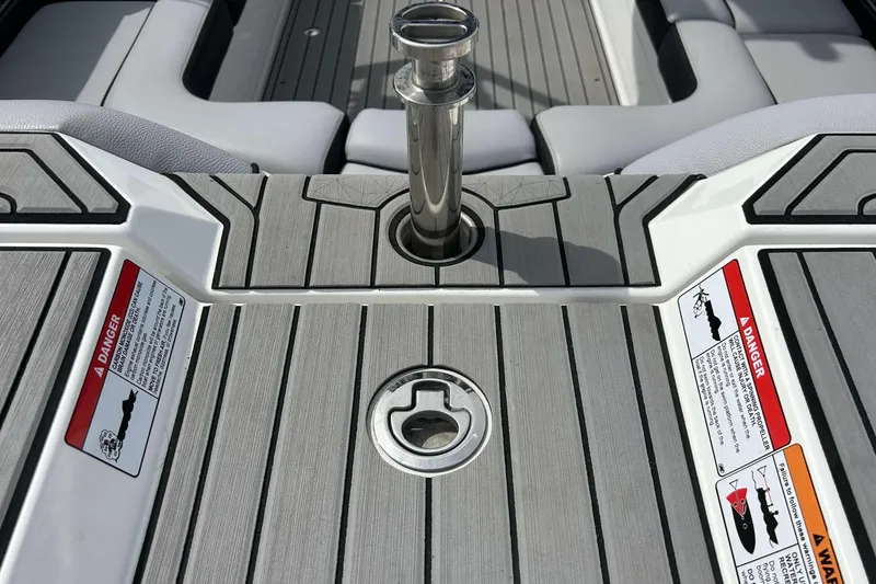 Slide: The Image of 2021 Nautique Super Air Nautique GS24 boat deck with safety warnings and metal fixture. - 7