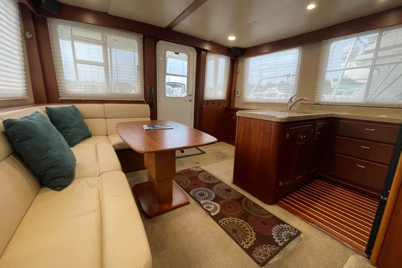 Slide: The Image of Interior of 2006 American Tug 41, featuring cozy seating and a compact kitchen area. - 11