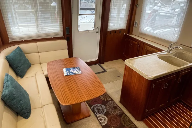 Slide: The Image of Interior of 2006 American Tug 41 with cozy seating, wooden table, and kitchenette. - 13