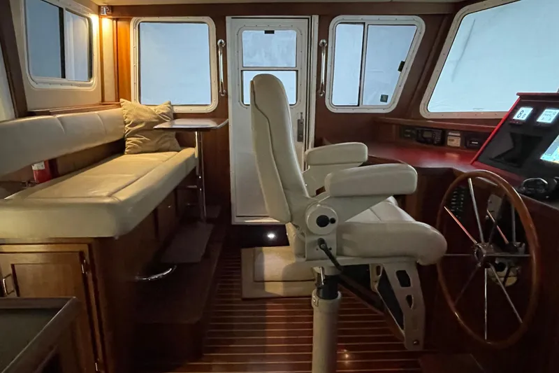 Slide: The Image of Interior of 2006 American Tug 41, featuring helm station, seating, and wooden accents. - 2