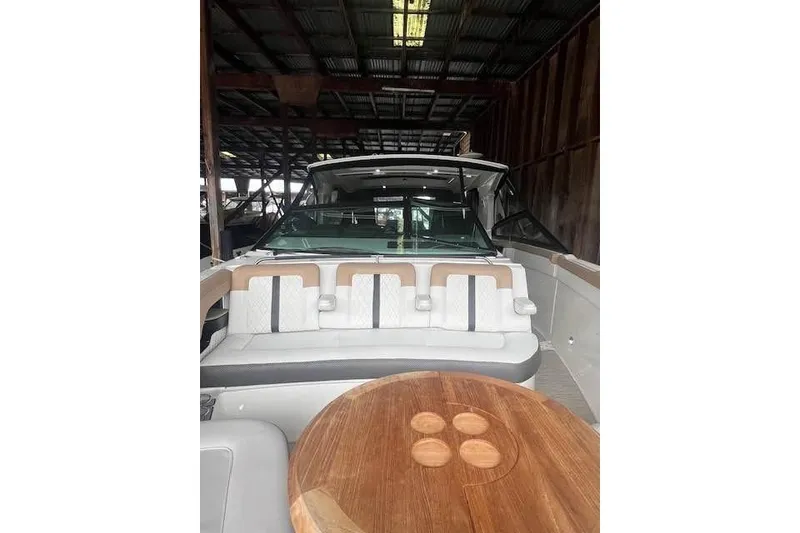 Slide: The Image of 2018 Sea Ray SLX 400 boat interior with seating and wooden table in a covered dock. - 12