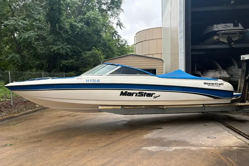 The Image of 1999 MasterCraft MariStar 230 Sport boat in storage, featuring a sleek white and blue design. - 0