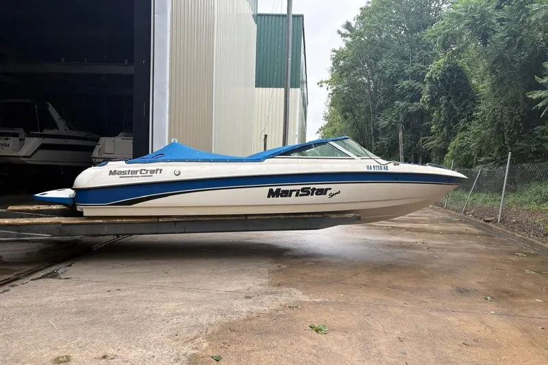 Slide: The Image of 1999 MasterCraft MariStar 230 Sport boat on a trailer near a storage facility. - 3