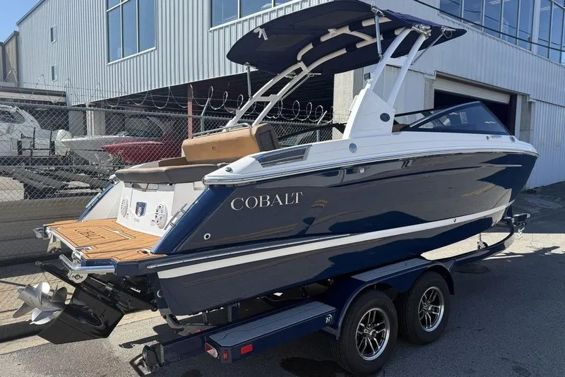 Slide: The Image of 2026 Cobalt R4 boat on trailer, sleek design, blue and white exterior, docked outdoors. - 5