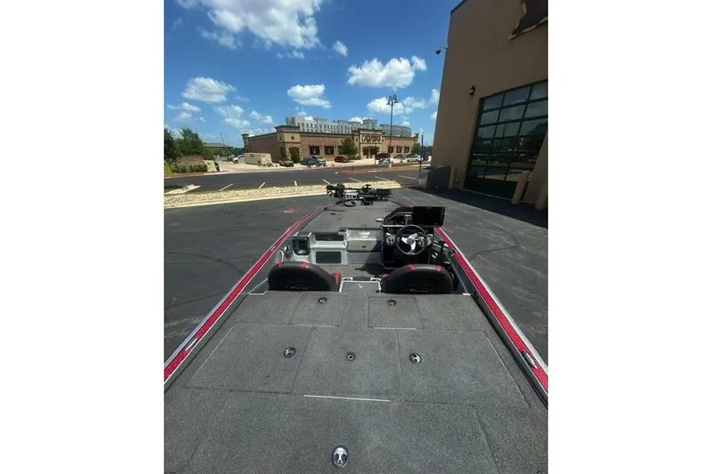 Slide: The Image of 2022 Triton 19 TrX Patriot boat parked outdoors under a clear blue sky. - 8