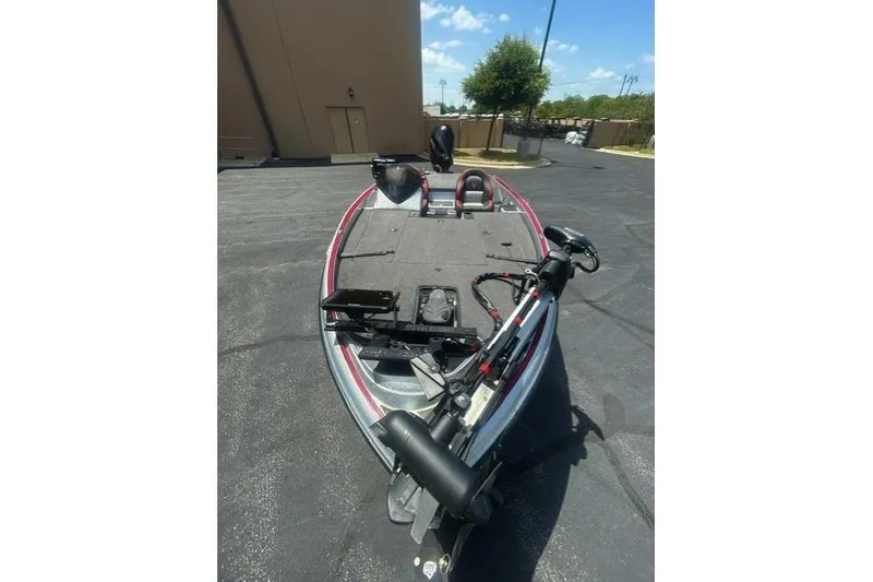 Slide: The Image of 2022 Triton 19 TrX Patriot bass boat parked outdoors on sunny day. - 5