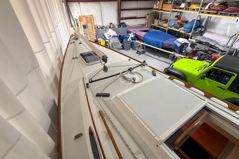 Slide: The Image of 1997 Alerion Express 28 sailboat stored indoors, alongside a green vehicle. - 7