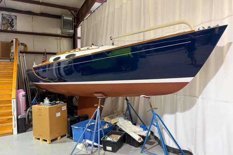 Slide: The Image of 1997 Alerion Express 28 sailboat in storage, blue hull, displayed on stands indoors. - 0