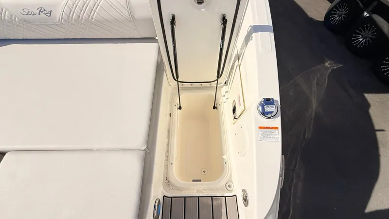 Slide: The Image of An open storage compartment on a Sea Ray SDX 250 Outboard boat, surrounded by white upholstery. - 17