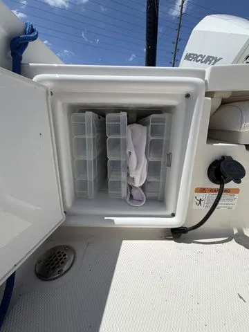 Slide: The Image of An open storage compartment on a boat with plastic containers and a towel. - 25