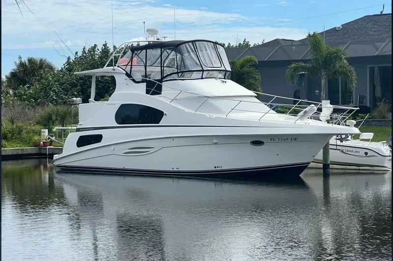 The Image of 2002 Silverton 39 Motor Yacht docked on calm water, surrounded by lush greenery. - 0