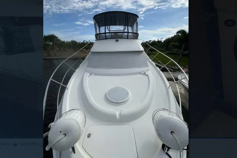 Slide: The Image of 2002 Silverton 39 Motor Yacht with sleek white deck and clear sky backdrop. - 2