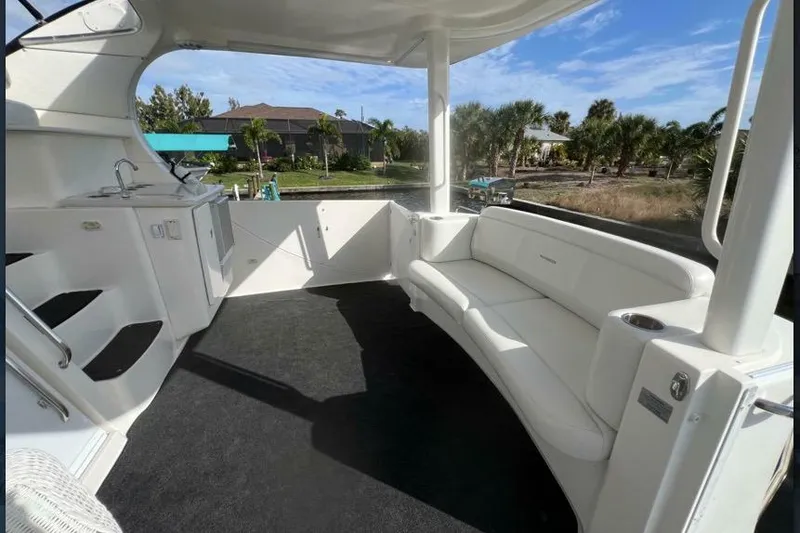 Slide: The Image of 2002 Silverton 39 Motor Yacht interior with white seating and kitchenette, docked near palm trees. - 10
