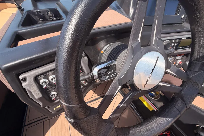 Slide: The Image of Steering wheel and dashboard of a 2019 Moomba Makai boat, featuring control switches. - 14