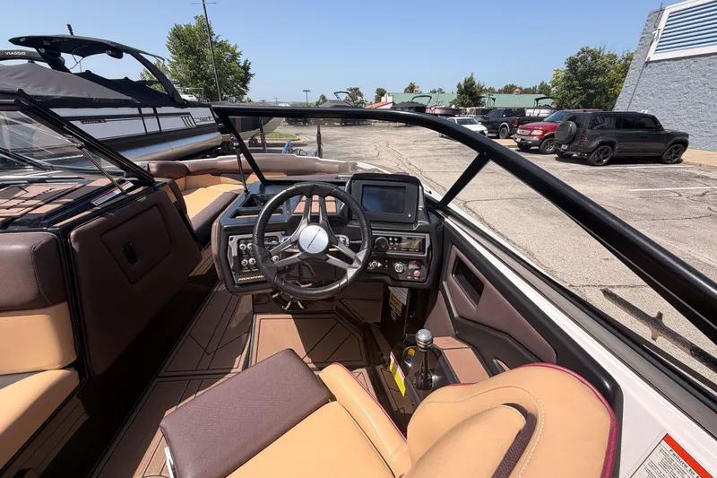 Slide: The Image of 2019 Moomba Makai boat interior with steering wheel and dashboard in a parking lot. - 33