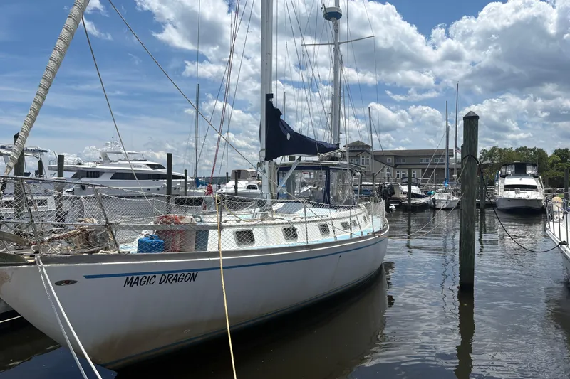 Slide: The Image of 1980 Gulfstar 50 CC Ketch sailboat named "Magic Dragon" docked at a marina under a cloudy sky. - 3