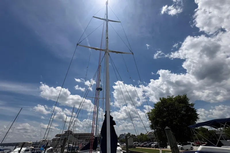 Slide: The Image of 1980 Gulfstar 50 CC Ketch sailboat mast under a bright, partly cloudy sky at a marina. - 9