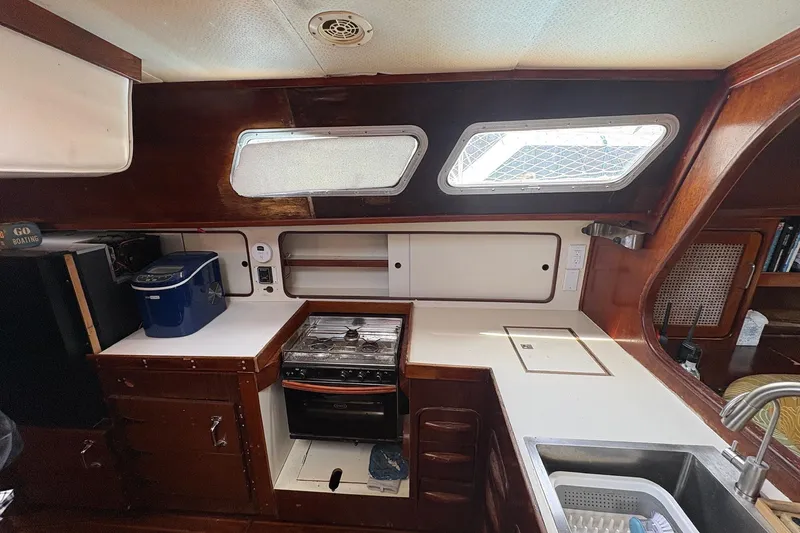 Slide: The Image of Interior of 1980 Gulfstar 50 CC Ketch, featuring a compact kitchen with stove and sink. - 24