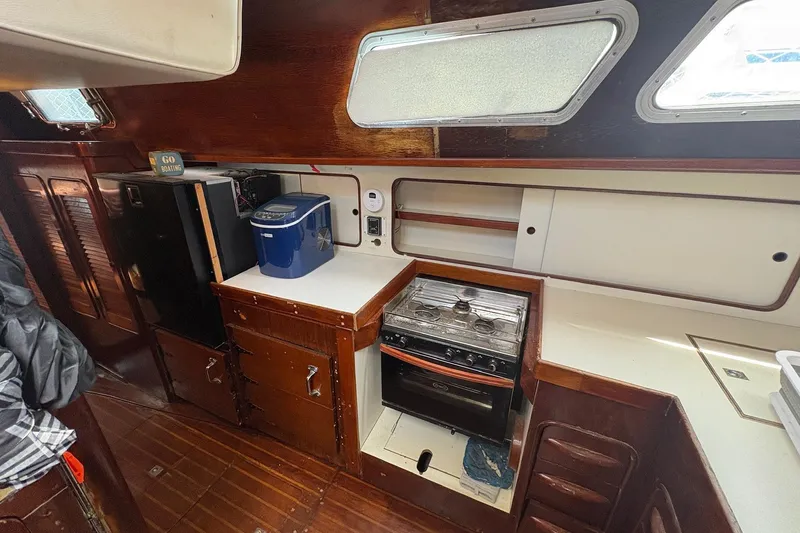 Slide: The Image of Interior of 1980 Gulfstar 50 CC Ketch, featuring a compact kitchen with stove and storage. - 25