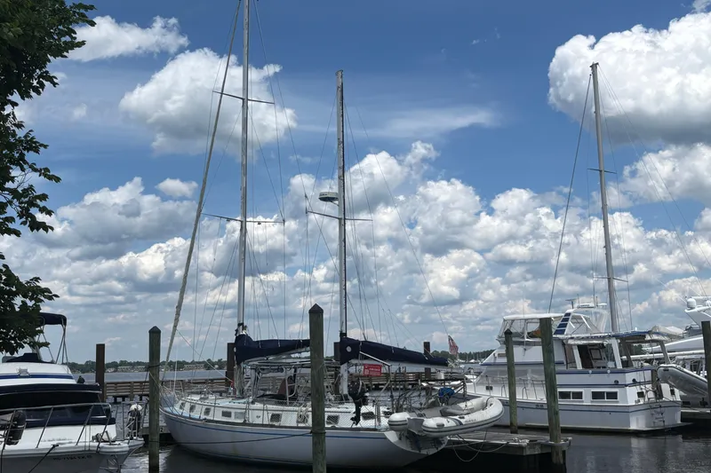 Slide: The Image of 1980 Gulfstar 50 CC Ketch sailboat docked under a partly cloudy sky. - 2