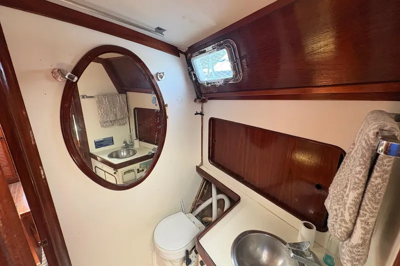 Slide: The Image of 1980 Gulfstar 50 CC Ketch bathroom with oval mirror, sink, and wooden accents. - 38