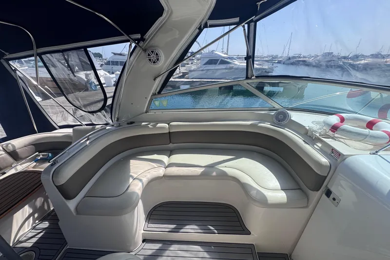 Slide: The Image of 2003 Rinker Fiesta Vee 312 boat interior with cushioned seating and marina view. - 13