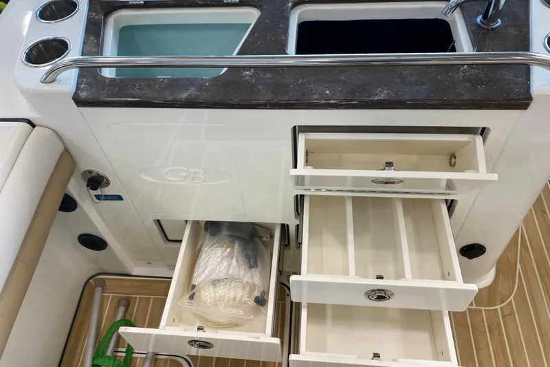 Slide: The Image of 2016 World Cat Glacier Bay Edition 2740 Dual Console boat interior with open storage drawers and sink. - 32