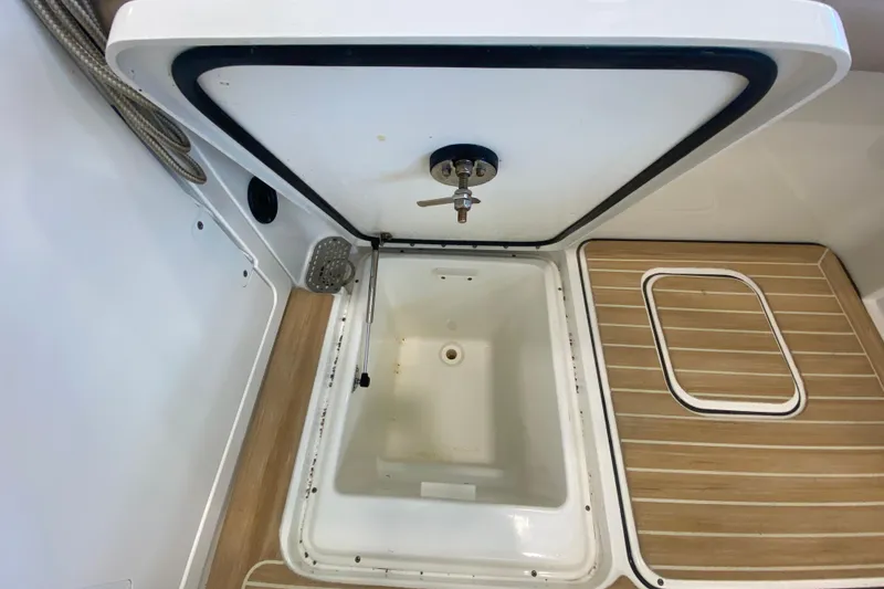 Slide: The Image of 2016 World Cat Glacier Bay Edition 2740 Dual Console storage compartment with open lid and wooden flooring. - 29