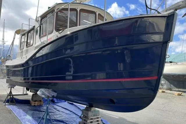 Slide: The Image of 2008 Ranger 2510 Bay Ranger boat on stands, blue hull, marina background. - 5