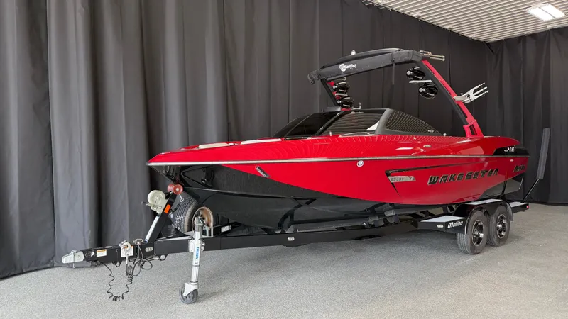 Slide: The Image of A red 2015 Malibu Wakesetter 23 LSV boat on a trailer in an indoor setting. - 2