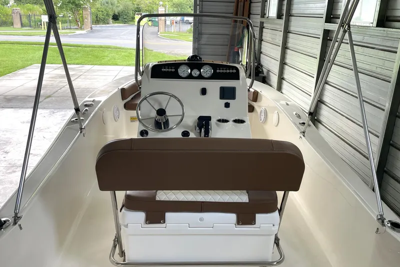 Slide: The Image of 2024 Pioneer 180 Islander boat interior with steering wheel and dashboard in a garage. - 7