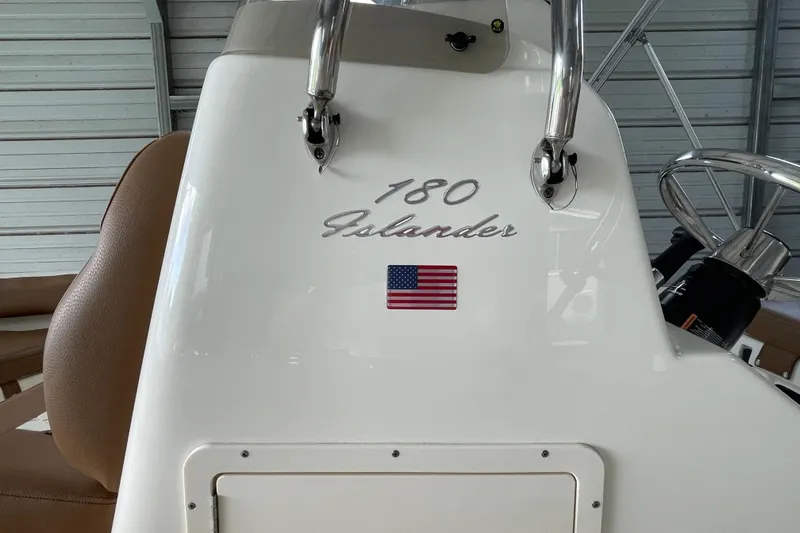Slide: The Image of 2024 Pioneer 180 Islander boat console with American flag emblem in a garage setting. - 12
