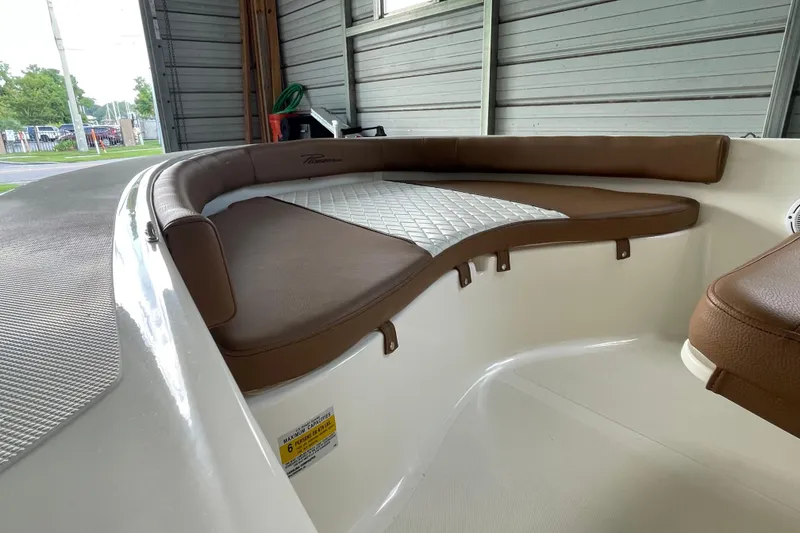 Slide: The Image of 2024 Pioneer 180 Islander boat interior with brown cushioned seating in a garage. - 13