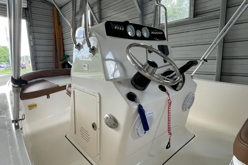 Slide: The Image of 2024 Pioneer 180 Islander boat console with steering wheel and gauges in a garage setting. - 11