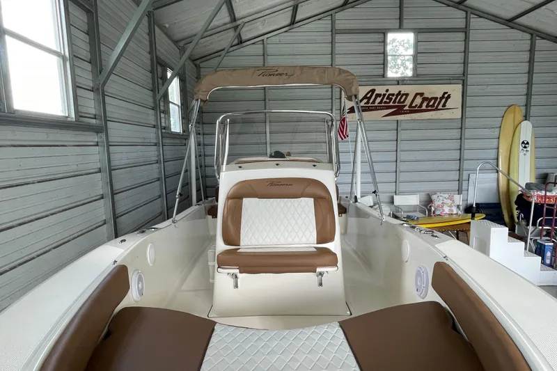 Slide: The Image of 2024 Pioneer 180 Islander boat in a garage, featuring brown and white seating. - 17