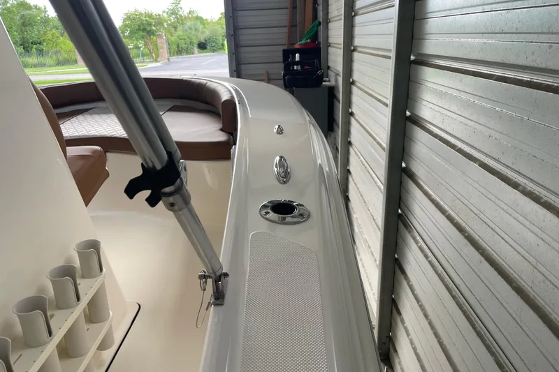 Slide: The Image of 2024 Pioneer 180 Islander boat interior with seating and rod holders in storage. - 21