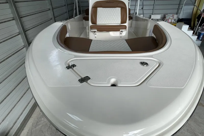Slide: The Image of 2024 Pioneer 180 Islander boat interior with white and brown seating in a garage. - 14