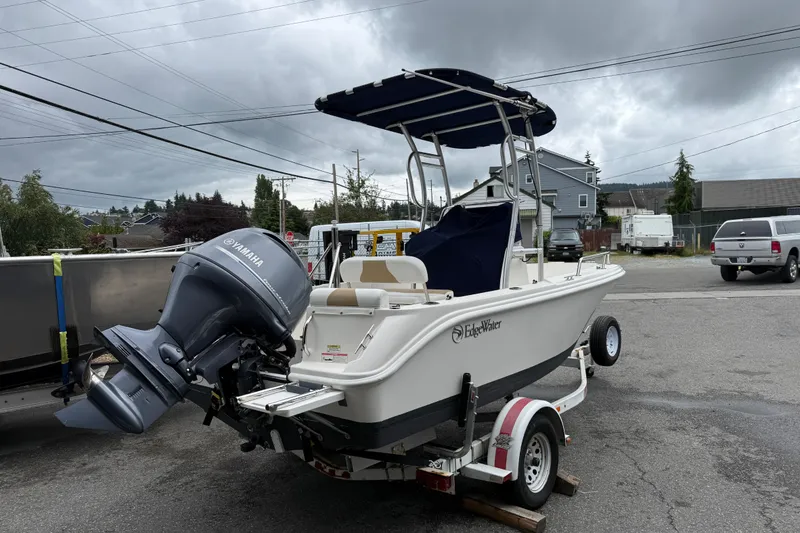 Slide: The Image of 2015 Edgewater 170CC boat with Yamaha motor on trailer, parked outdoors under cloudy skies. - 6