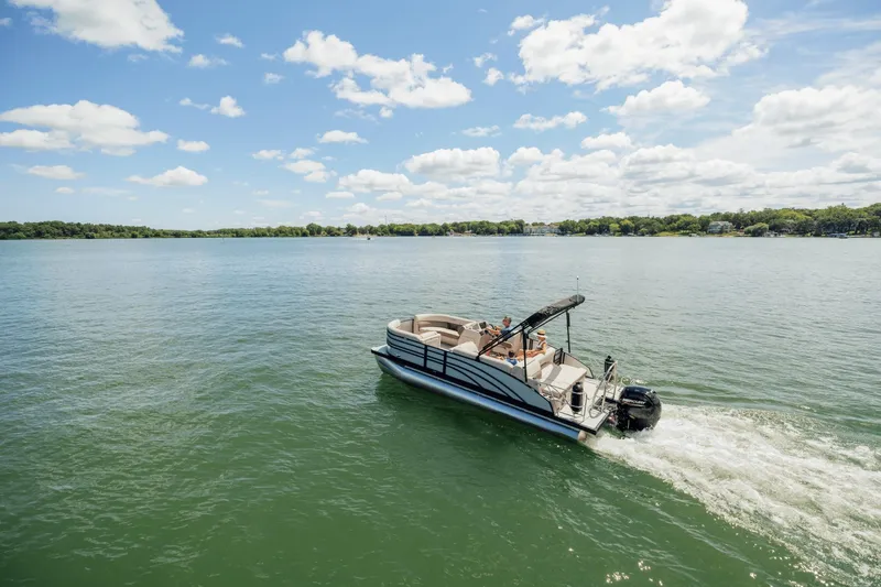 Slide: The Image of A Harris 210SL pontoon boat cruising on a calm lake under a blue sky. - 6