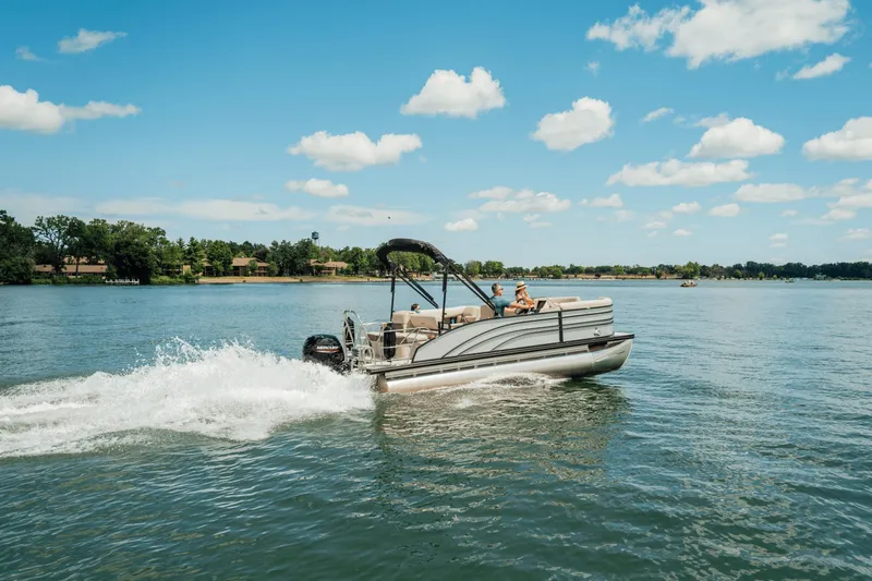 Slide: The Image of A Harris 210SL pontoon boat cruising on a calm lake under a blue sky. - 3