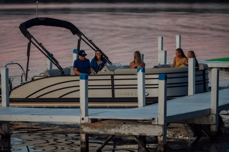 Slide: The Image of A group of people sits on a Harris 210SL pontoon boat at the dock during sunset. - 28