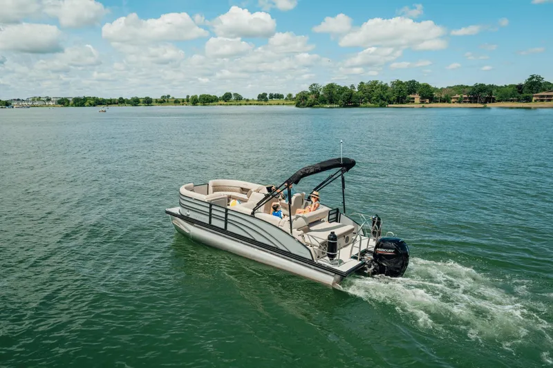 Slide: The Image of A Harris 210SL pontoon boat cruising on a calm lake under a blue sky. - 0